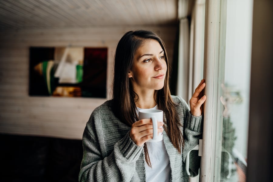 Mujer mira por la ventana durante el distanciamiento social
